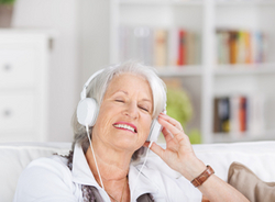 Seniorin hört mit Kopfhörern Musik.